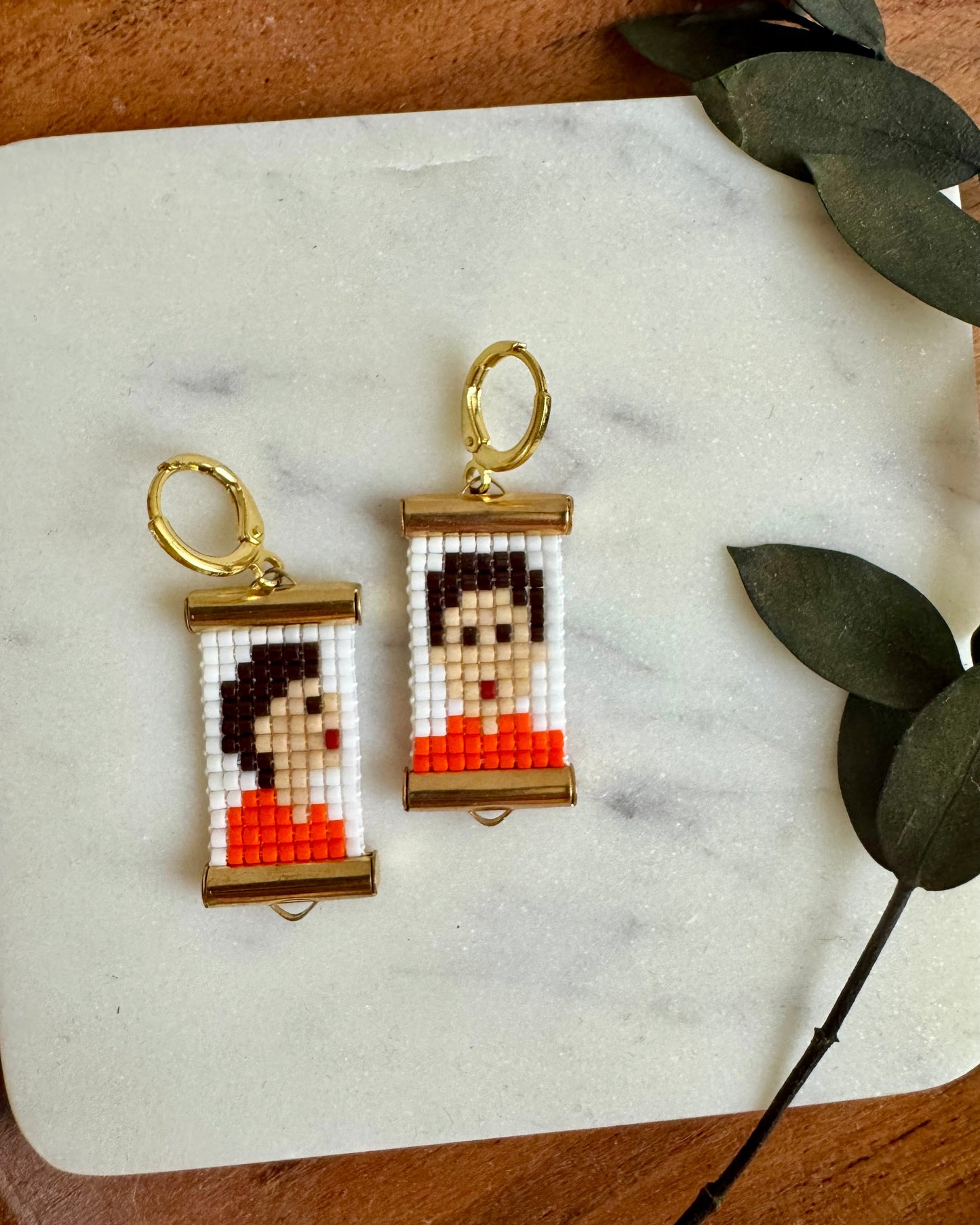 Two pixel art keychains on a marble surface with leaves in the background