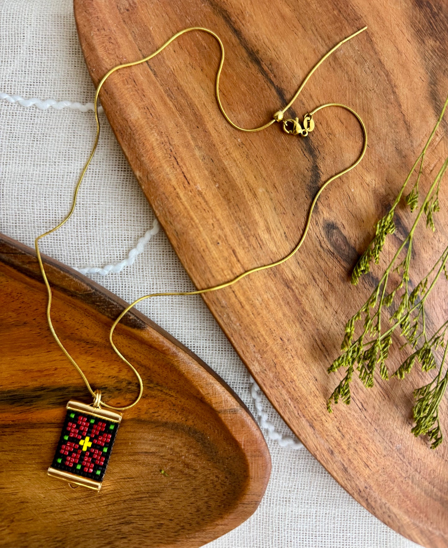 Gold necklace with a colorful pendant on a wooden surface