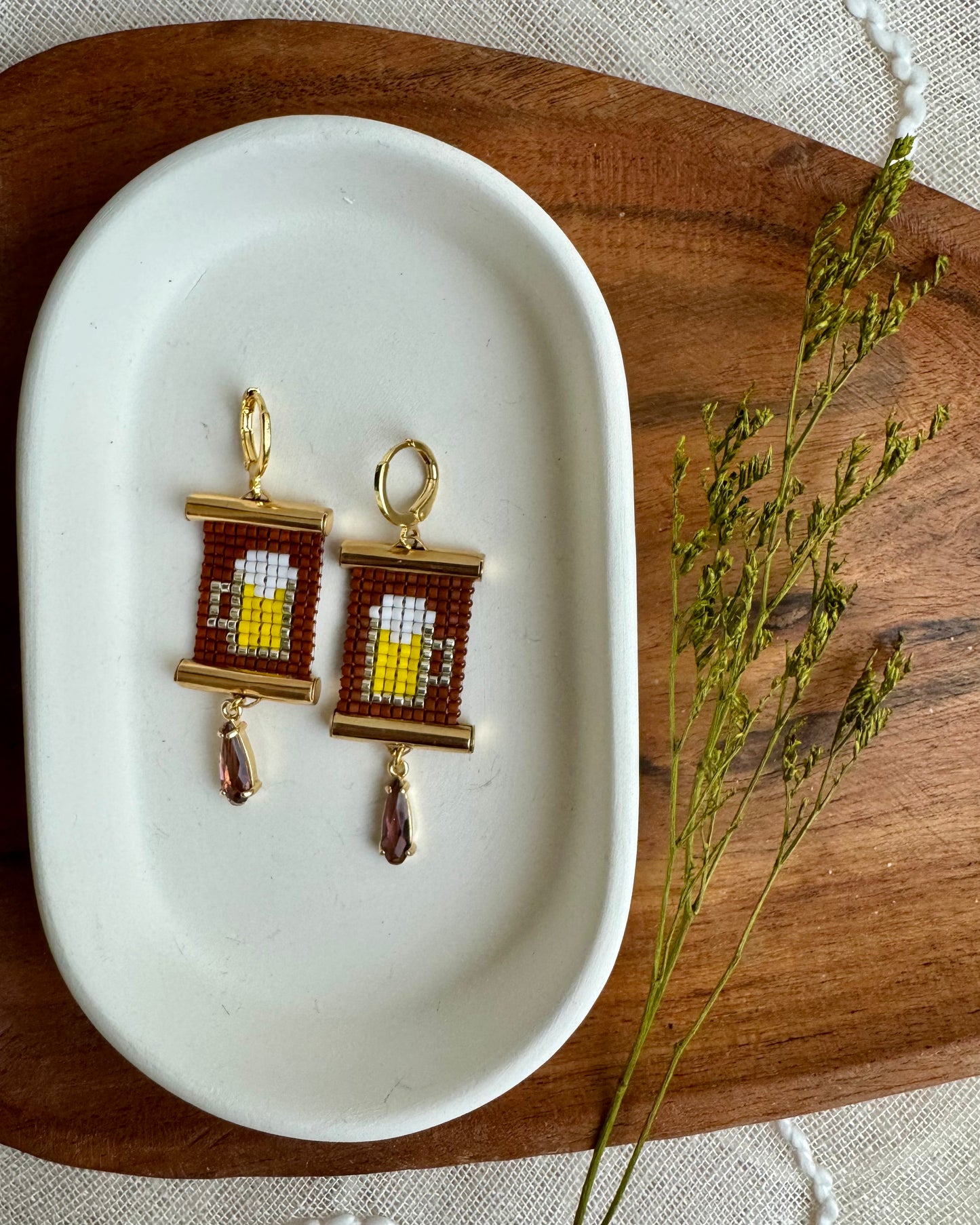 Pair of earrings on a white dish with a wooden background