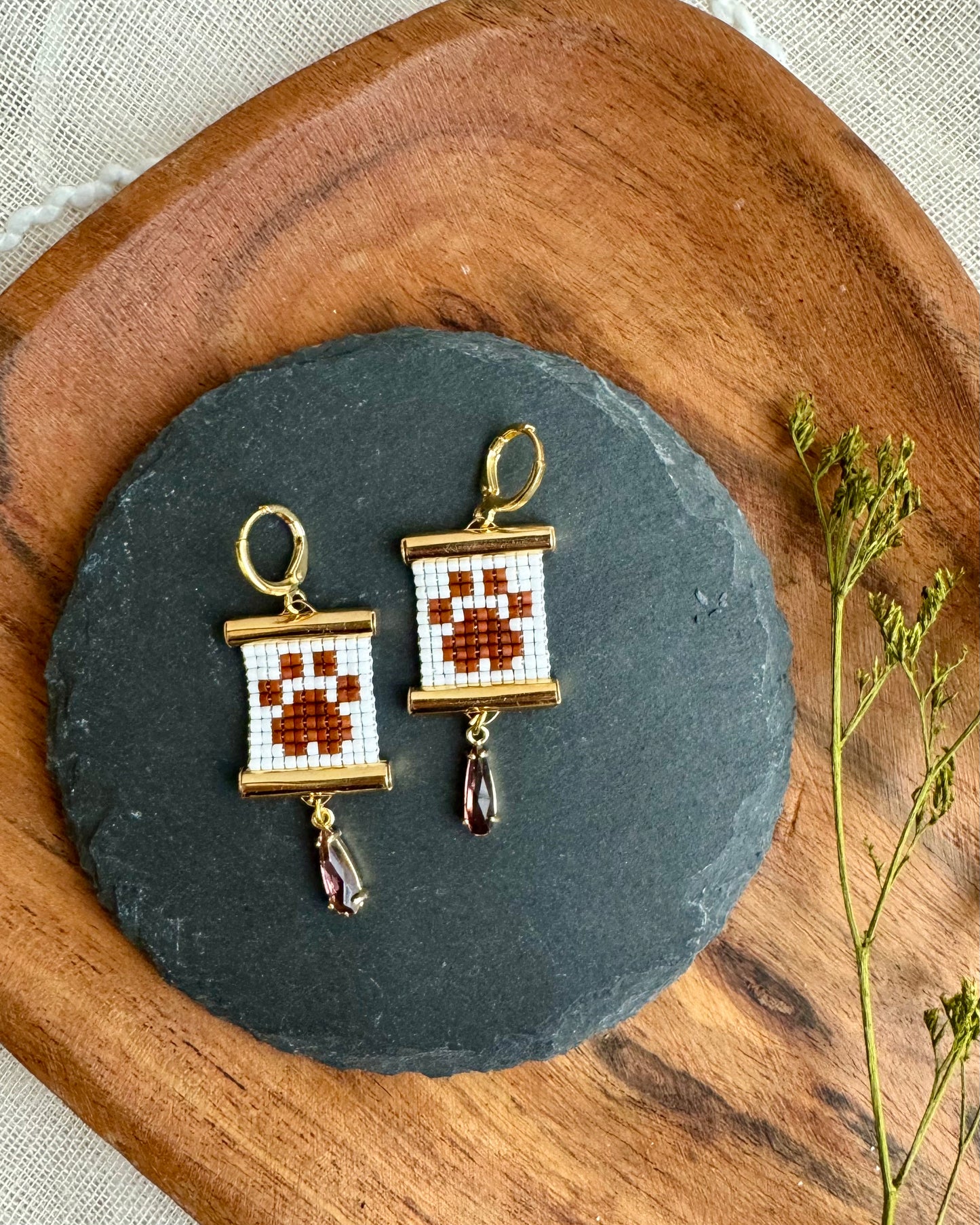 Pair of earrings on a dark slate stone with a wooden border