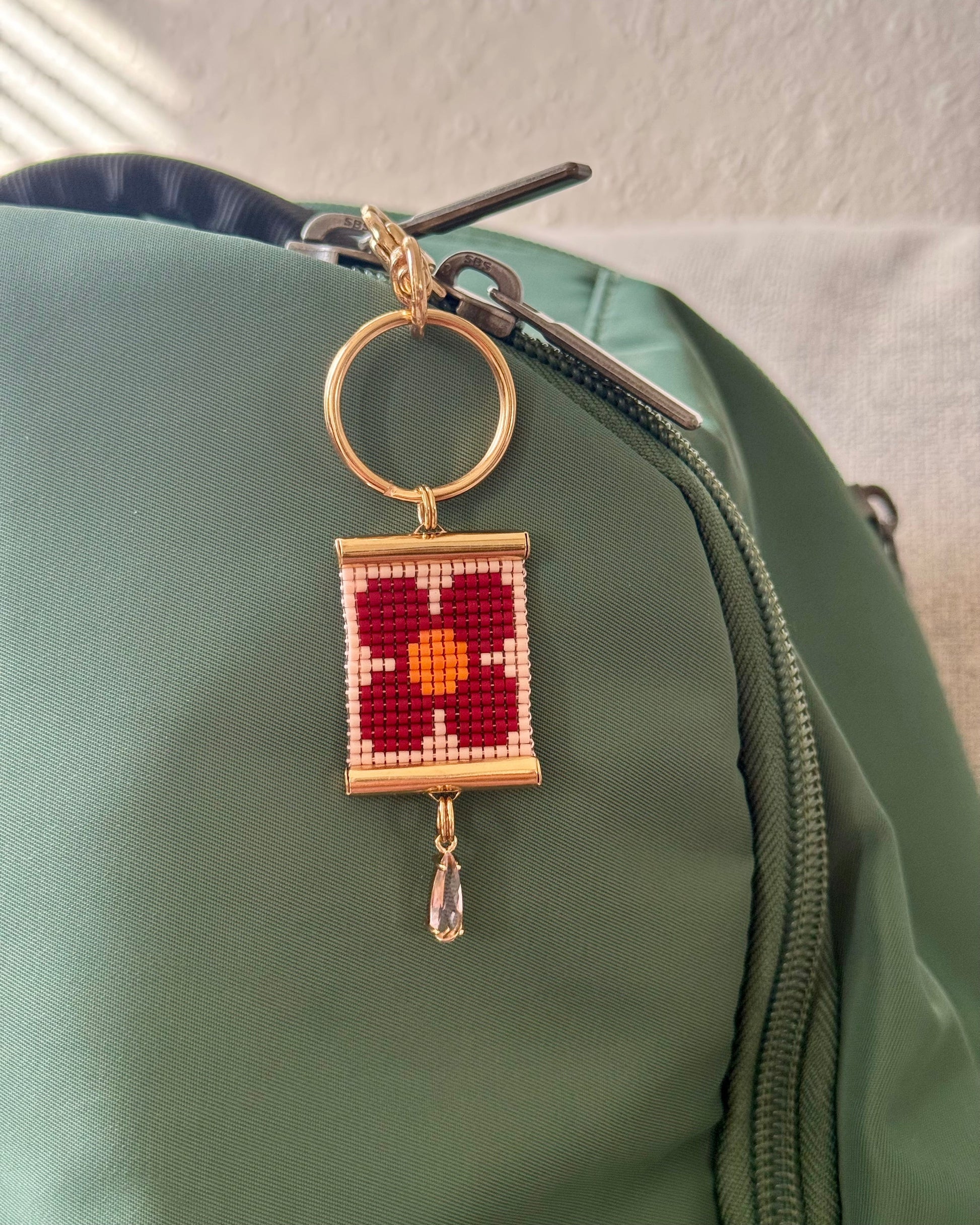 Decorative bag charm with a floral design on a green bag