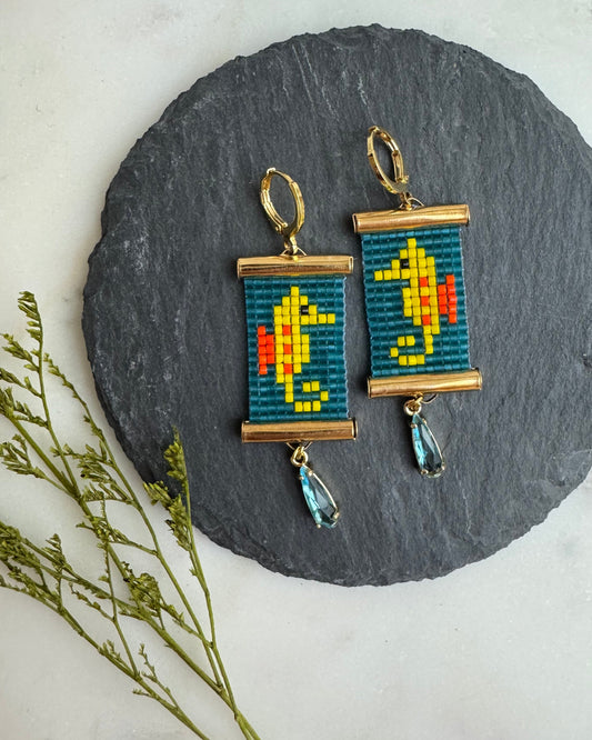 Pair of earrings with pixel art seahorse design on a round slate stone