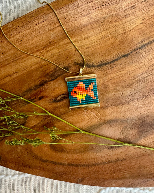 Necklace with a colorful fish pendant on a wooden surface