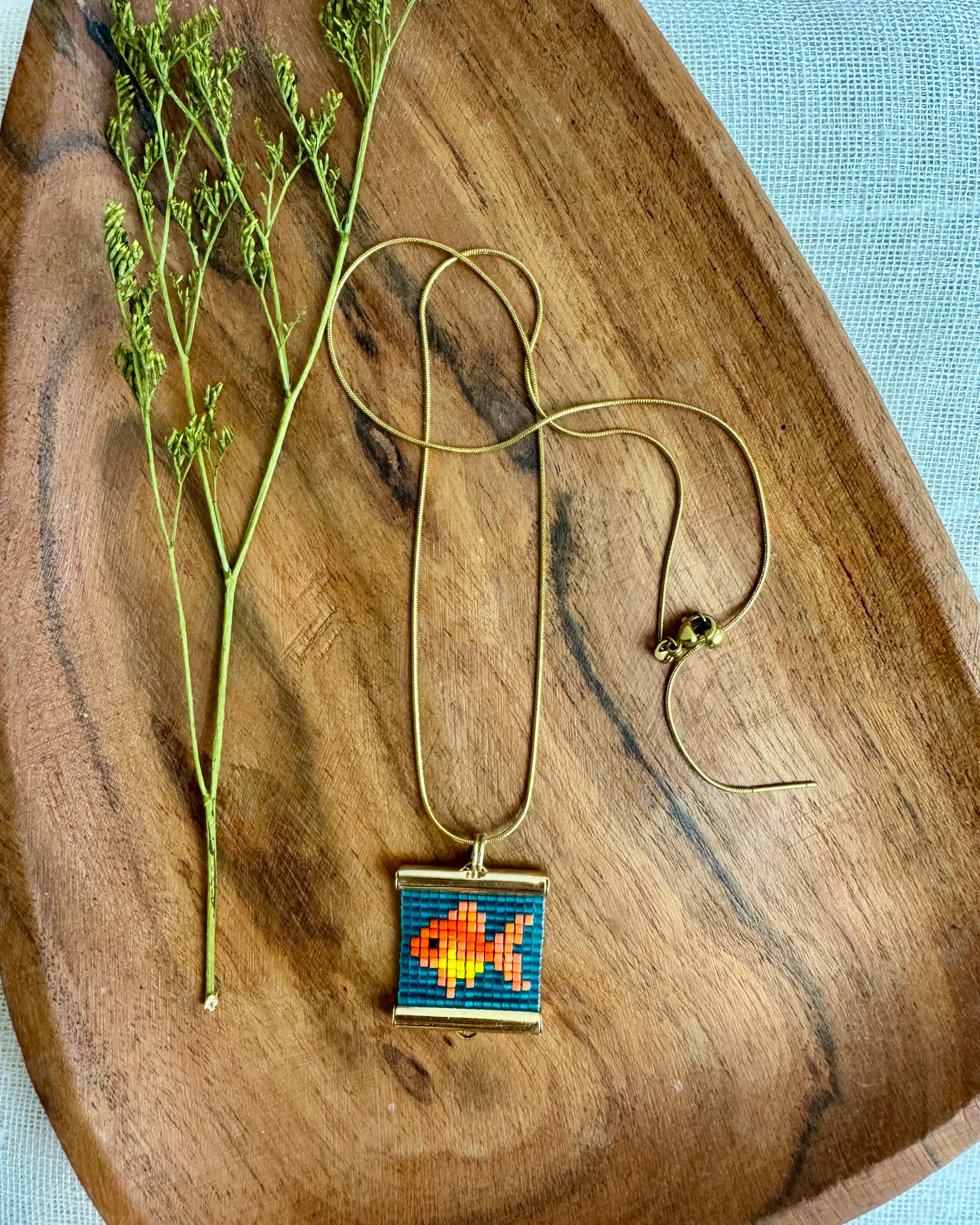 Necklace with a colorful fish pendant on a wooden surface