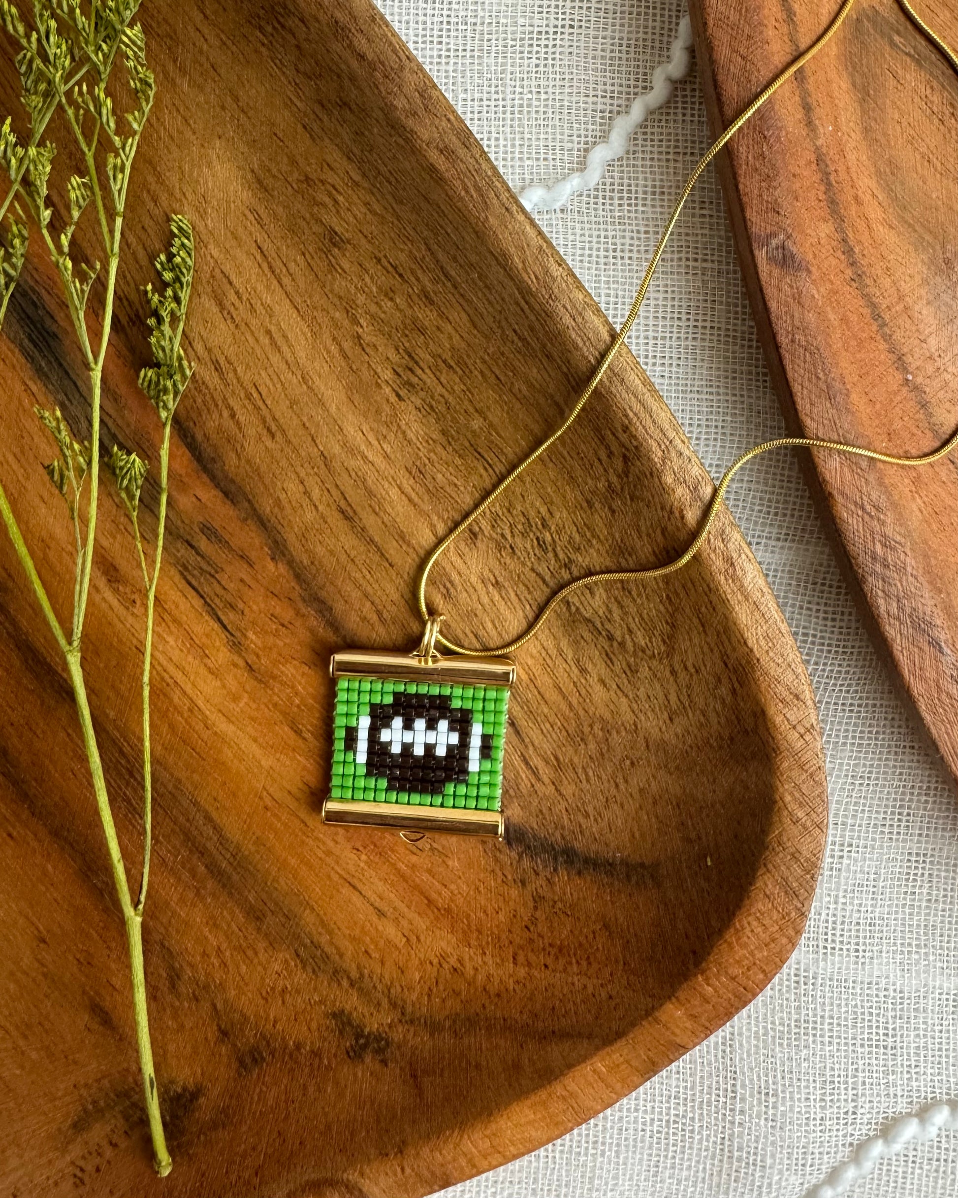 Necklace with a pixelated pendant on a wooden surface