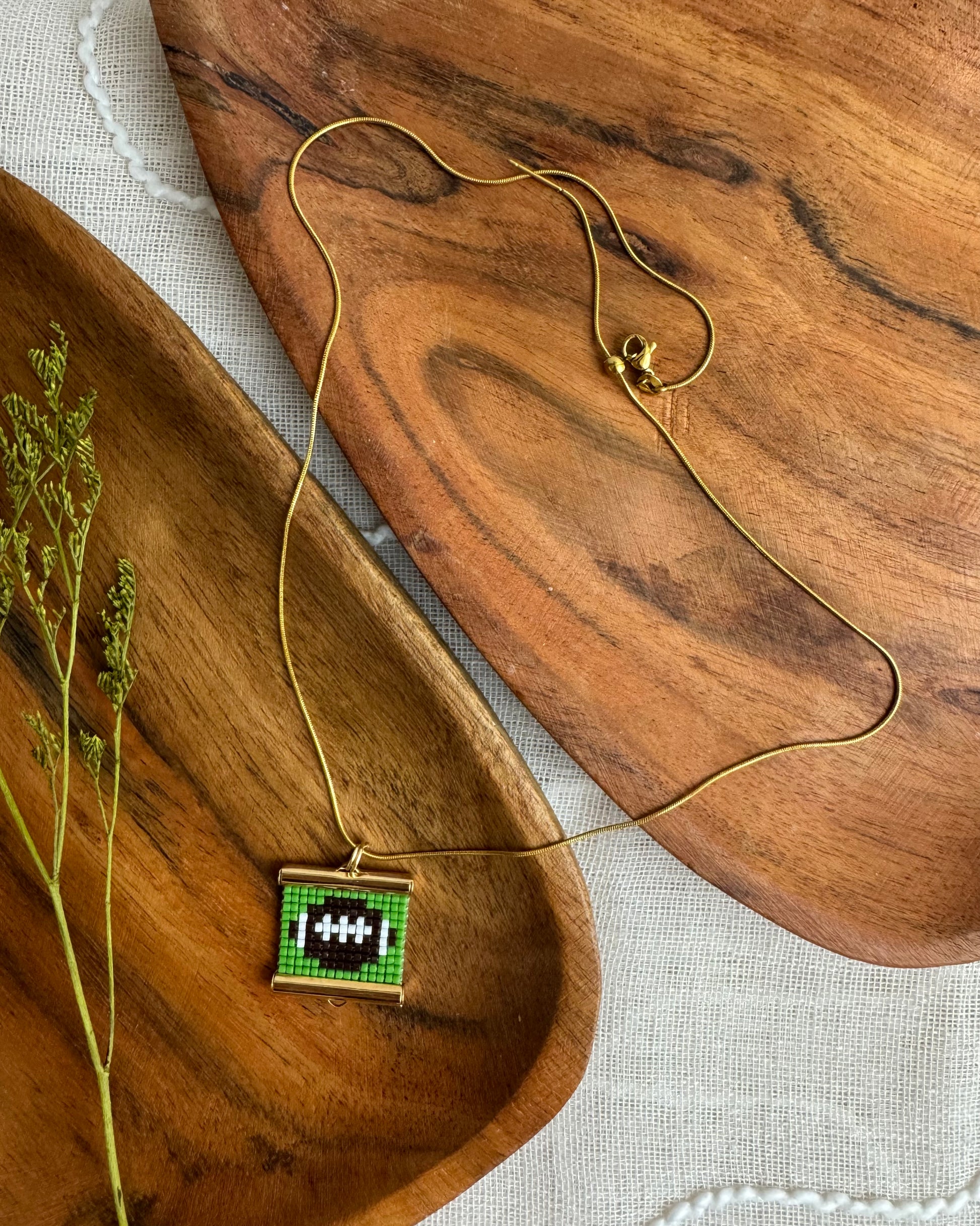 Necklace with a green and brown football pendant on a wooden surface