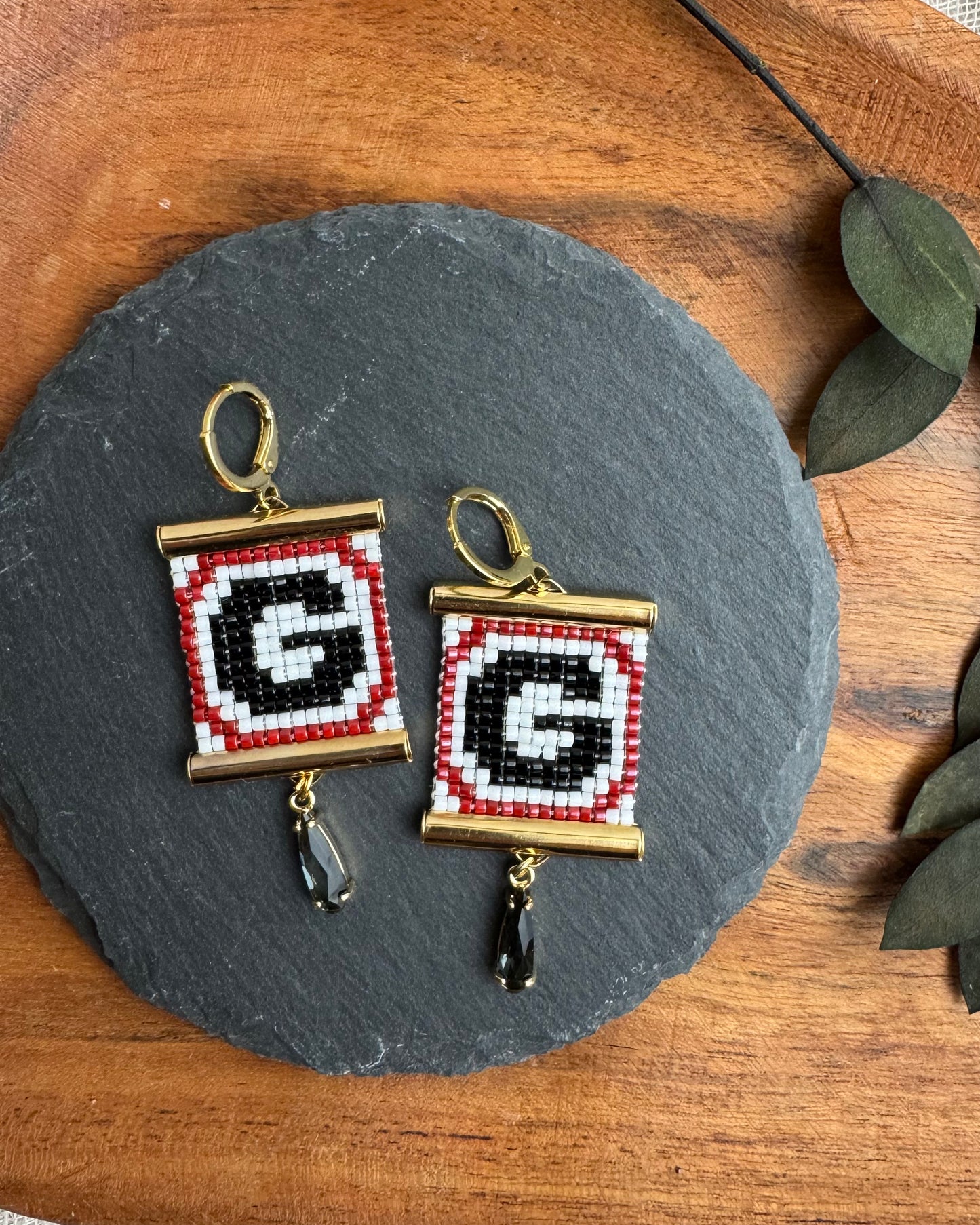 Pair of earrings with 'G' design on a slate stone