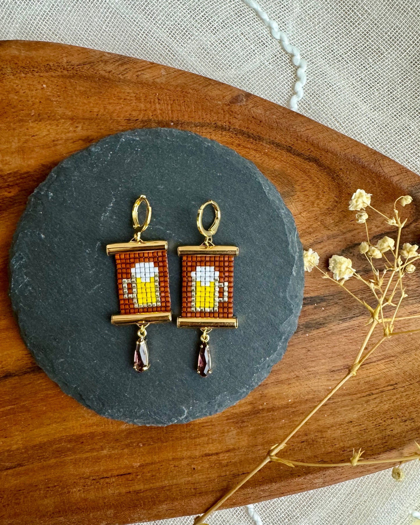 Pair of earrings on a slate stone with wooden and fabric background