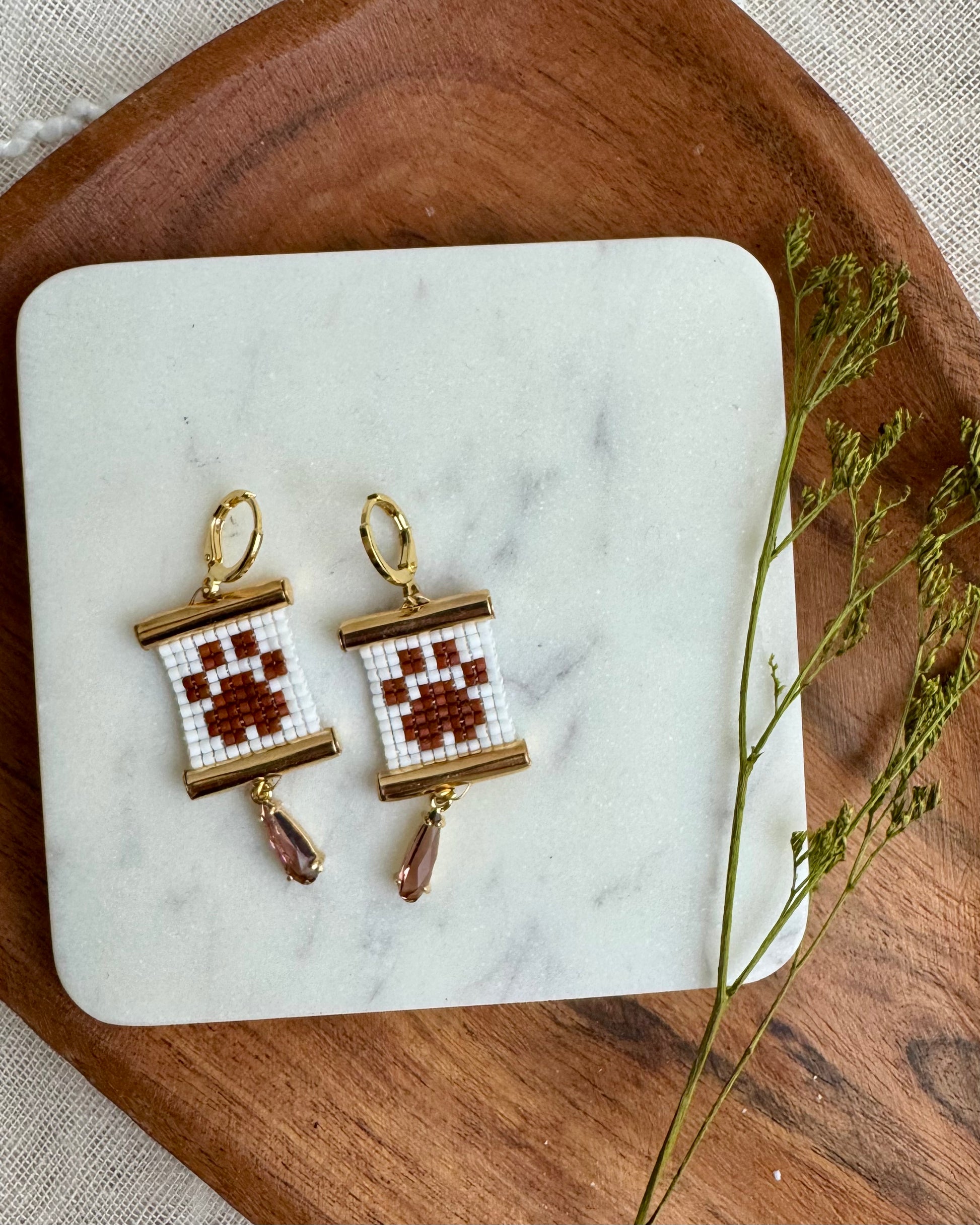 Pair of earrings on a marble surface with a wooden background