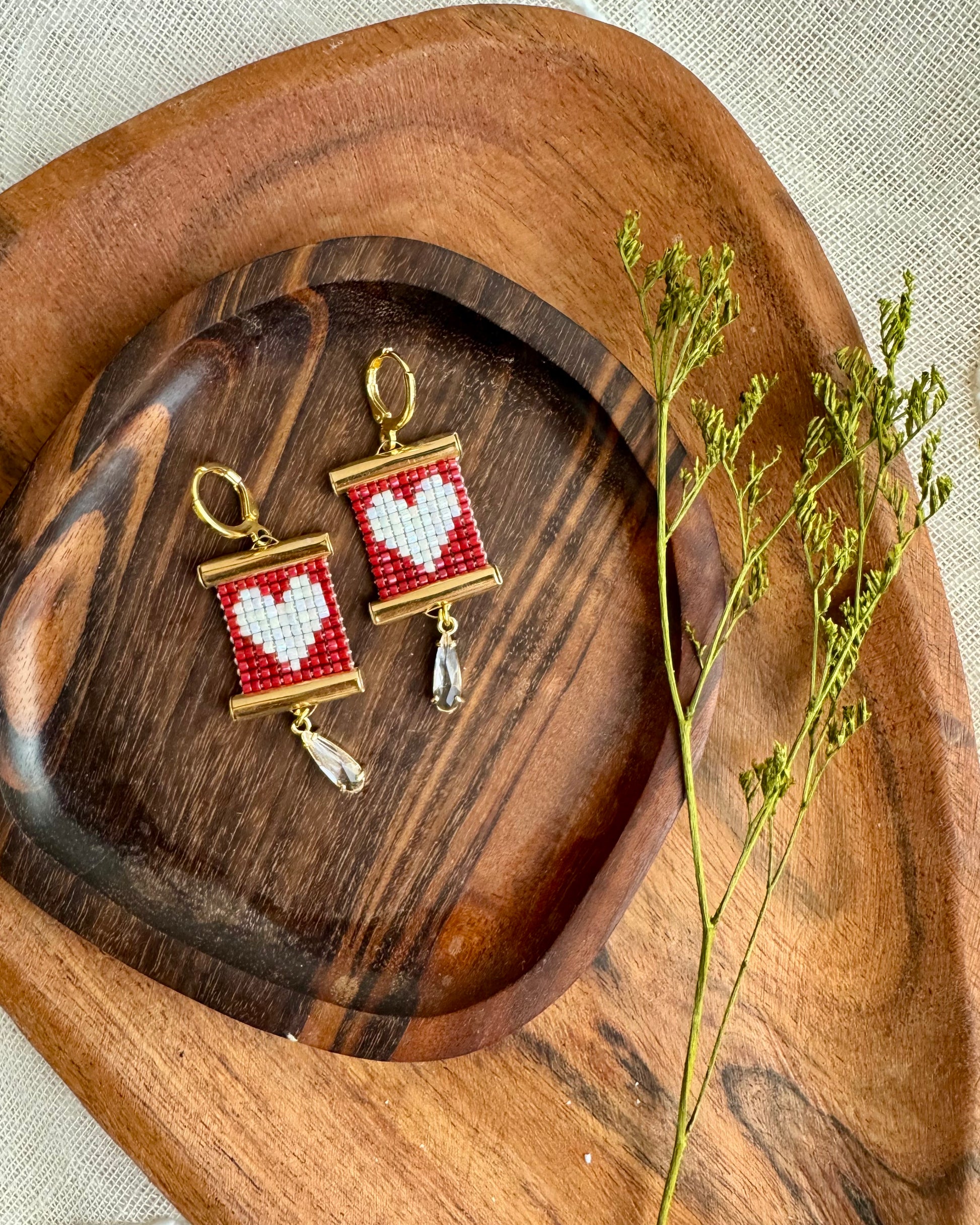 Pair of earrings with heart designs on a wooden surface