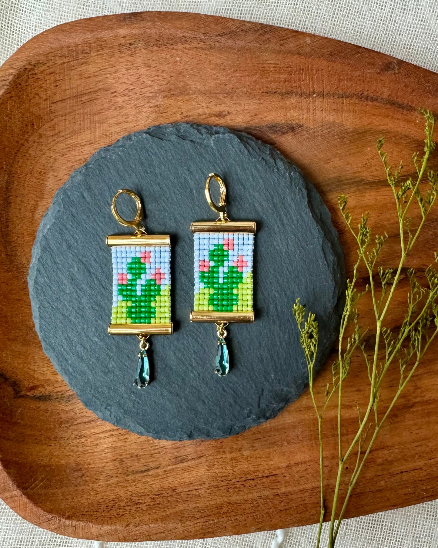Earrings with beaded cactus design on a wooden tray with a natural background