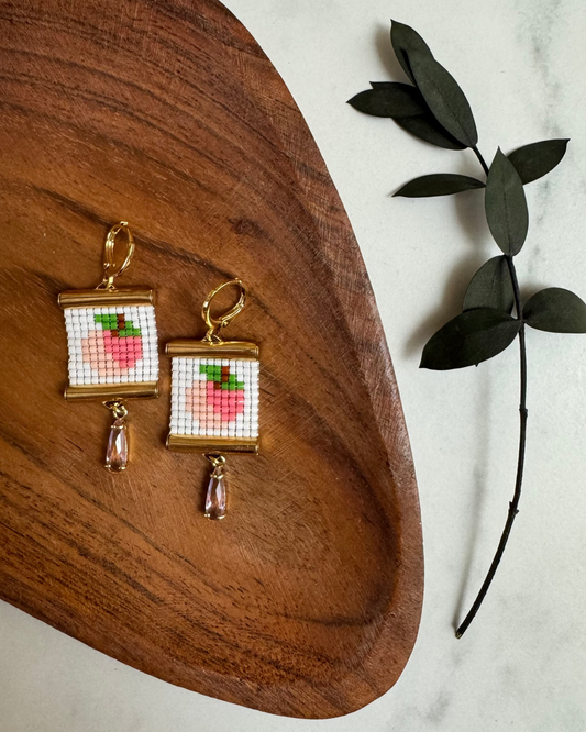 Beaded earrings with peach design on a wooden surface