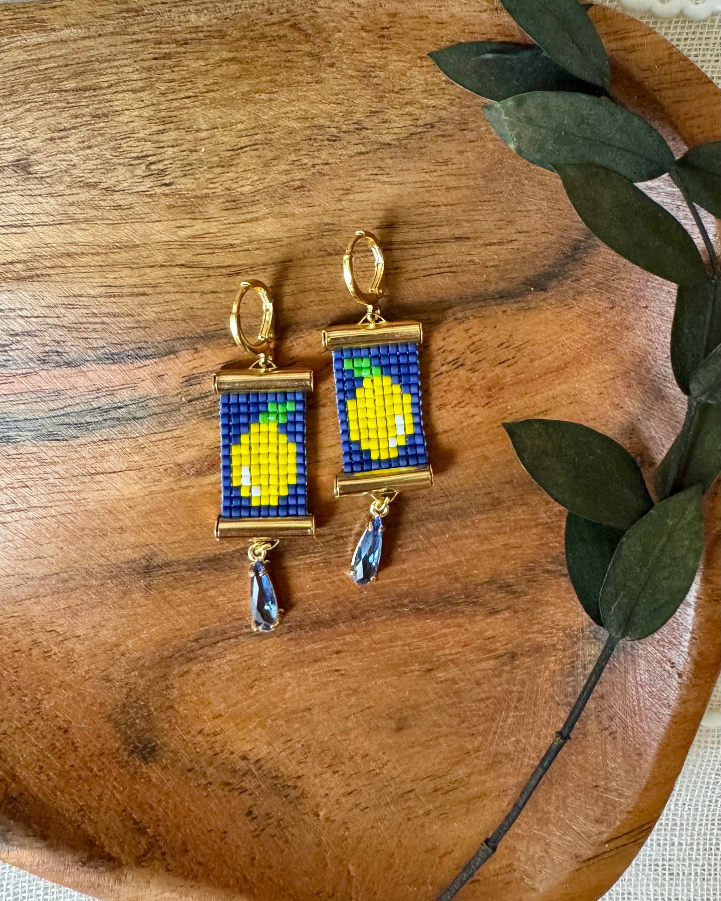 Pair of beaded earrings with lemon design on a wooden surface
