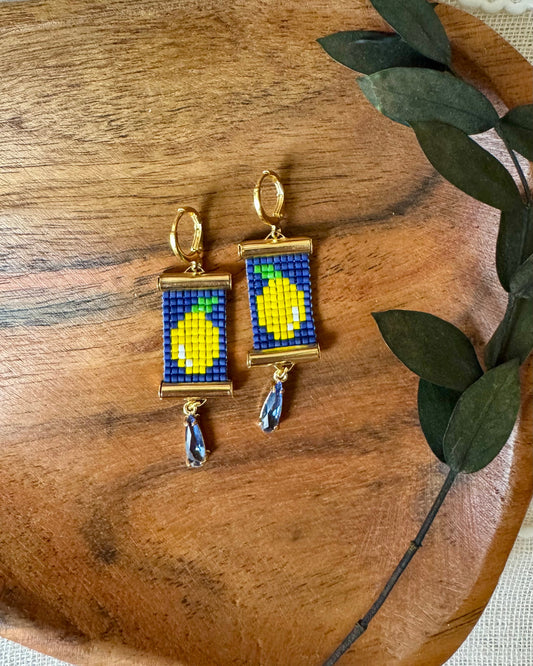 Pair of beaded earrings with lemon design on a wooden surface