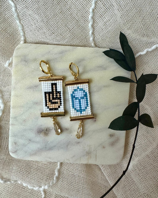 Pair of earrings with beaded designs on a marble surface