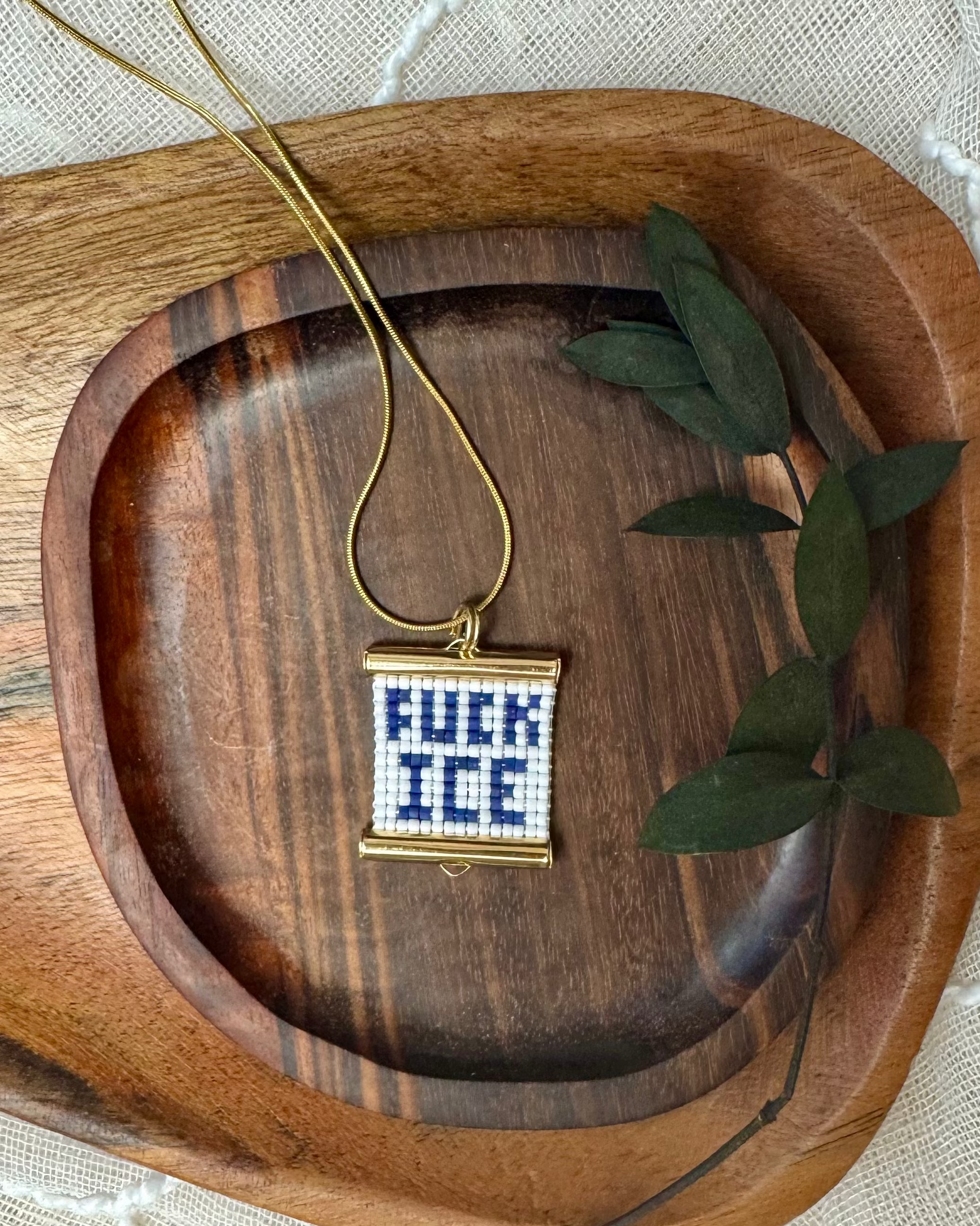 Neckalce with a beaded pendant on a wooden tray