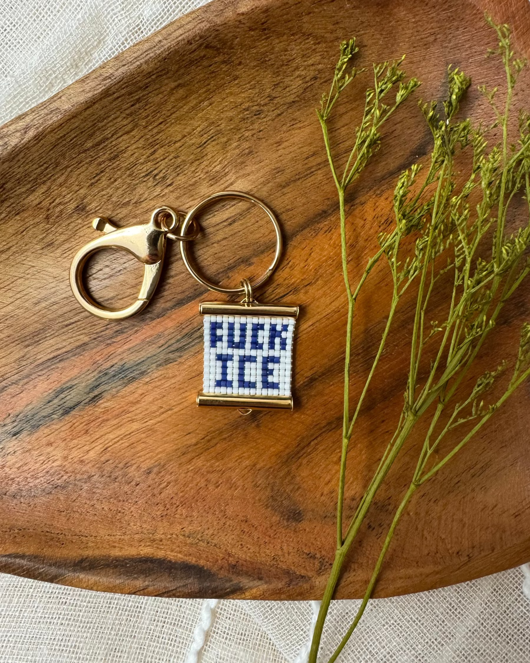 Beaded bag charm with relevant message on a wooden surface with dried plants