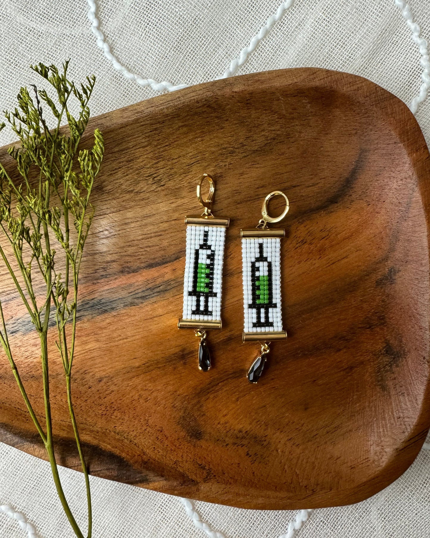 Pair of earrings on a wooden surface with a white lace background