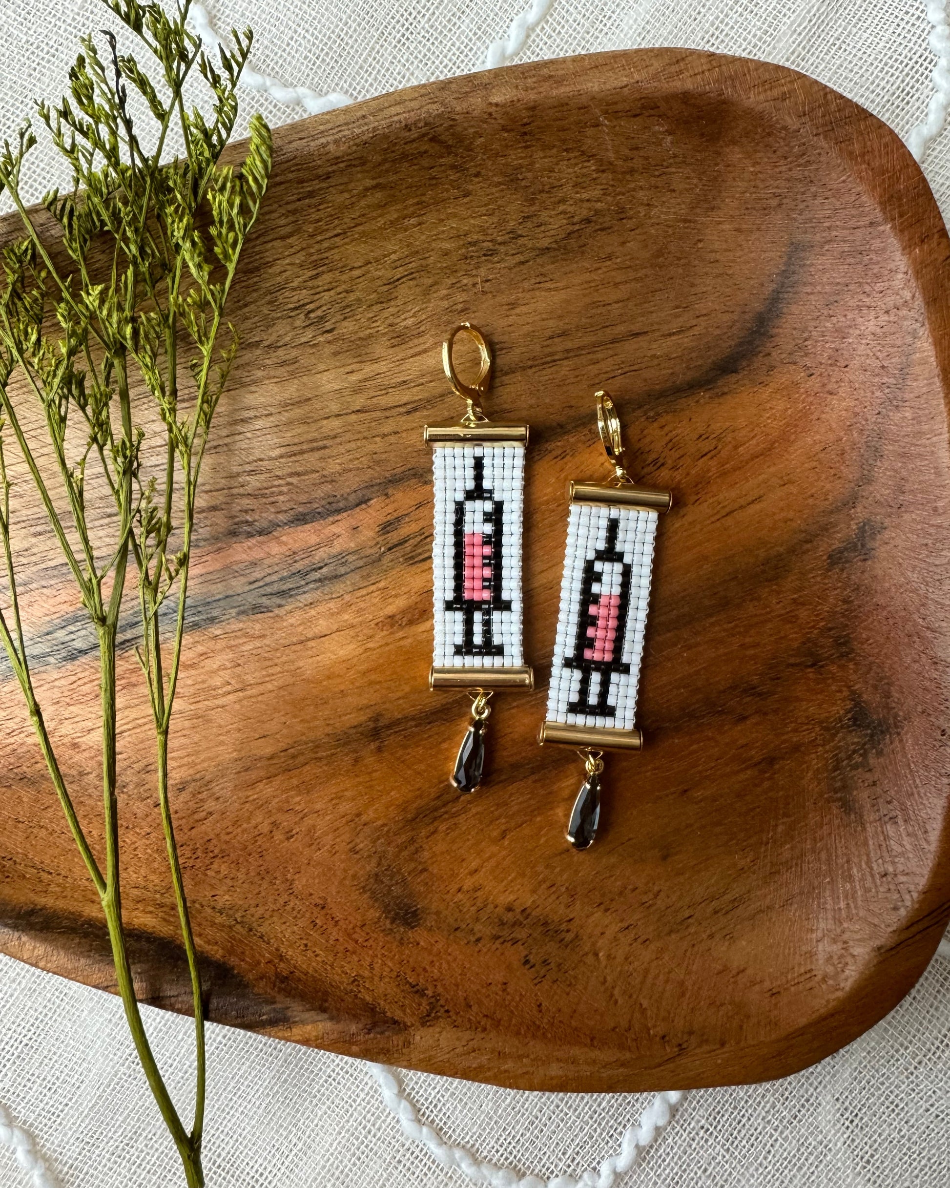 Pair of earrings with beaded design on a wooden tray