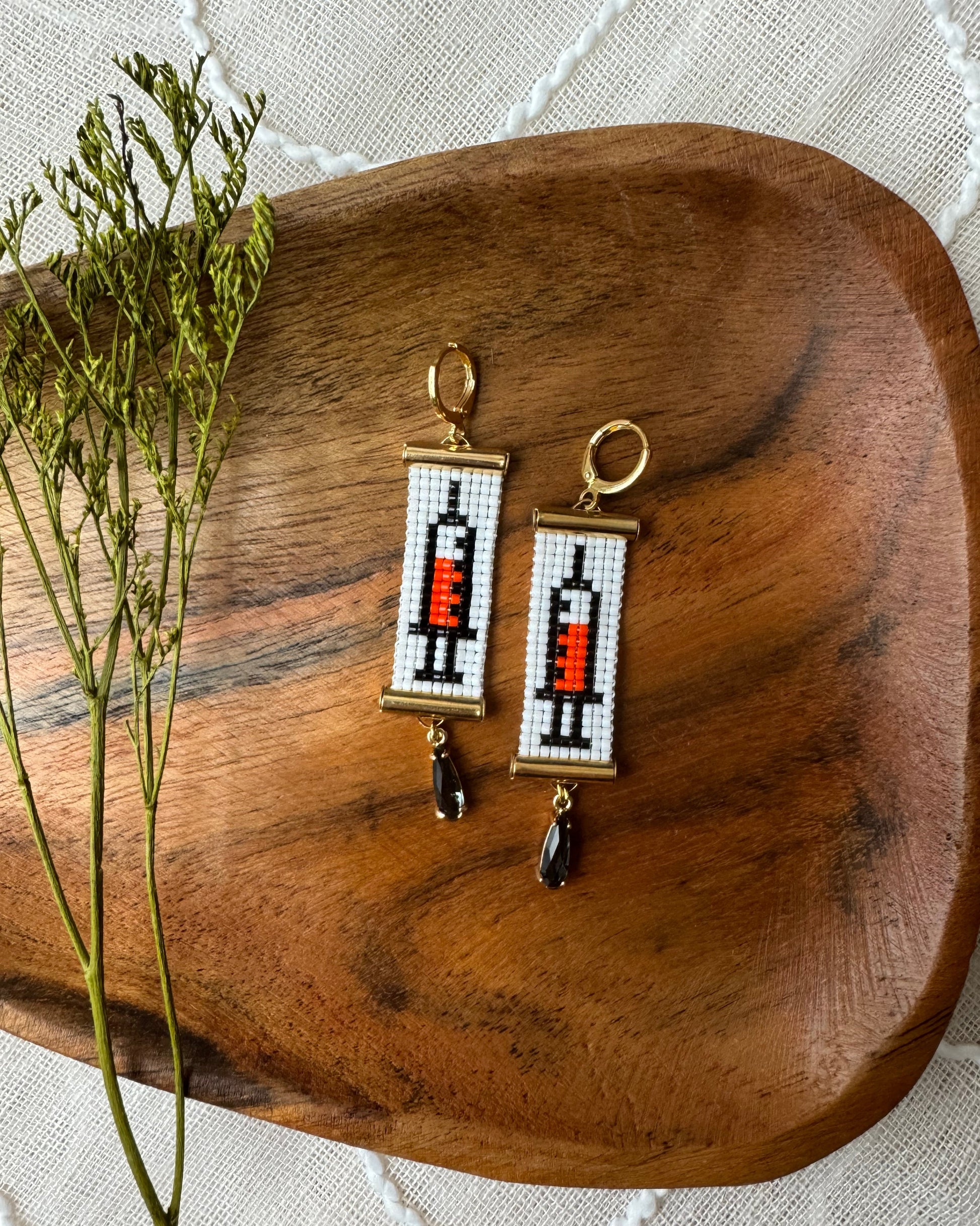 Pair of earrings on a wooden surface with a white fabric background