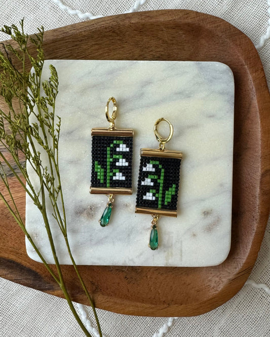 Pair of beaded earrings with floral design  on a marble surface.