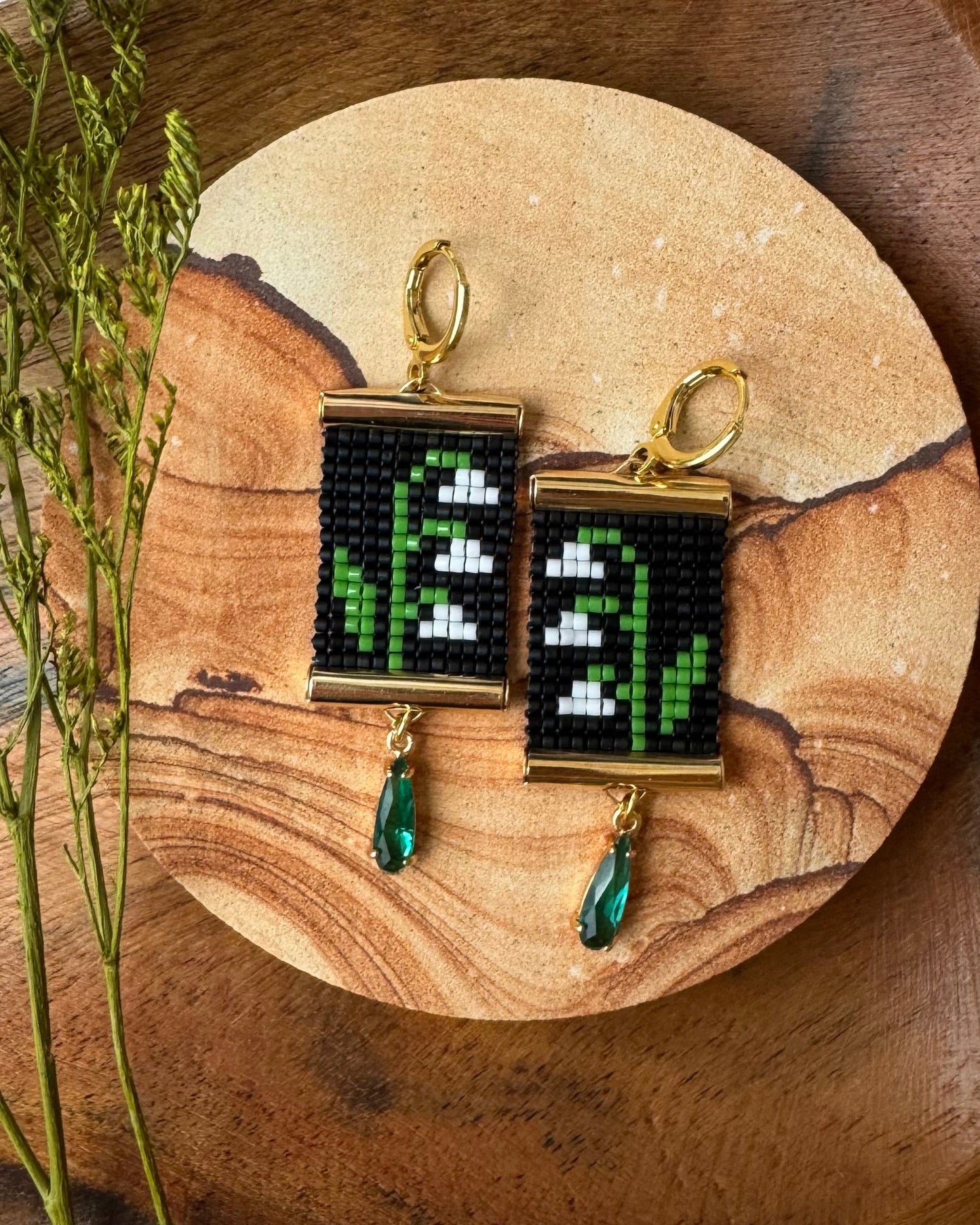 Beaded earrings with a floral design on a wooden surface with a white fabric background