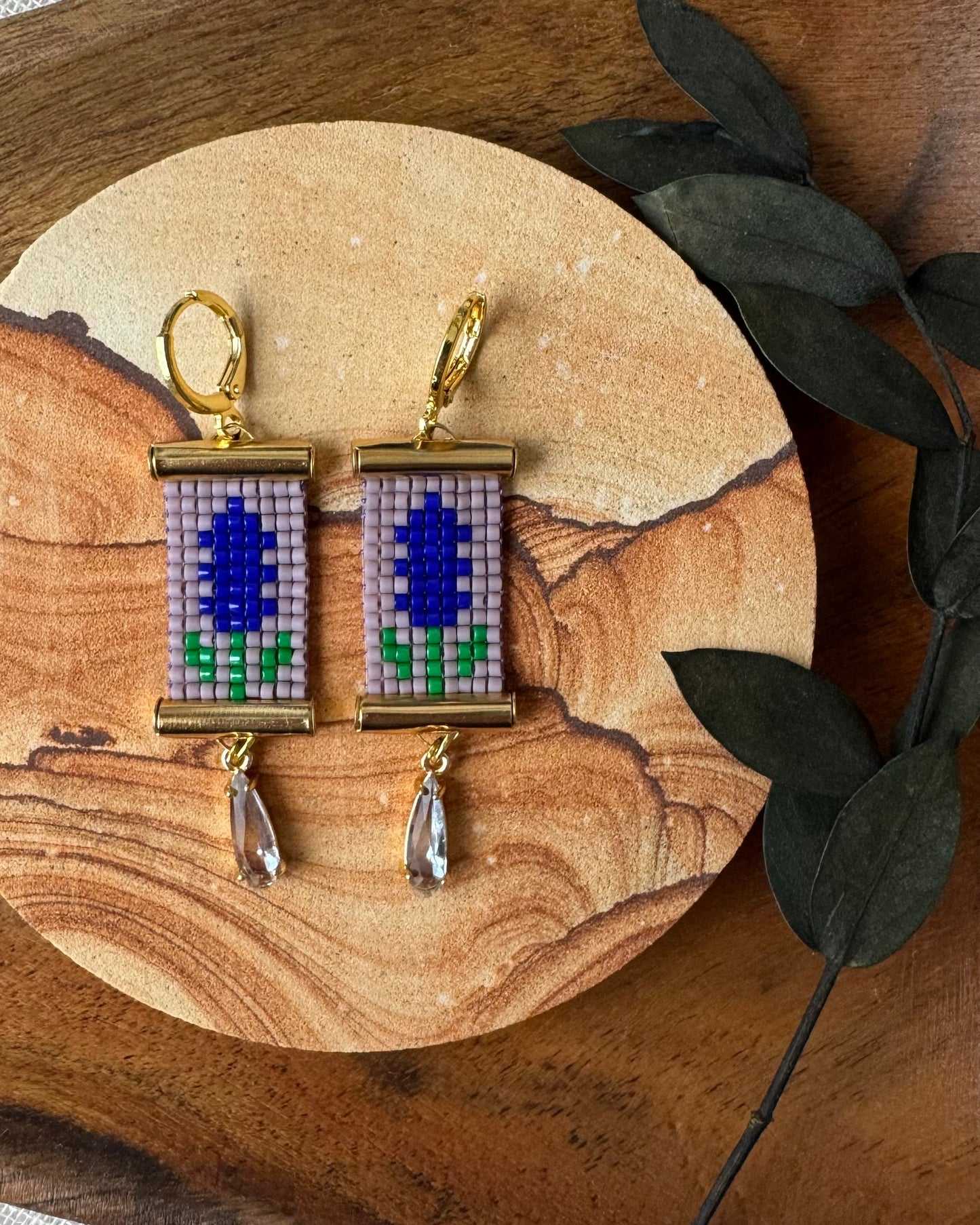 Pair of earrings with beaded floral design on a wooden surface