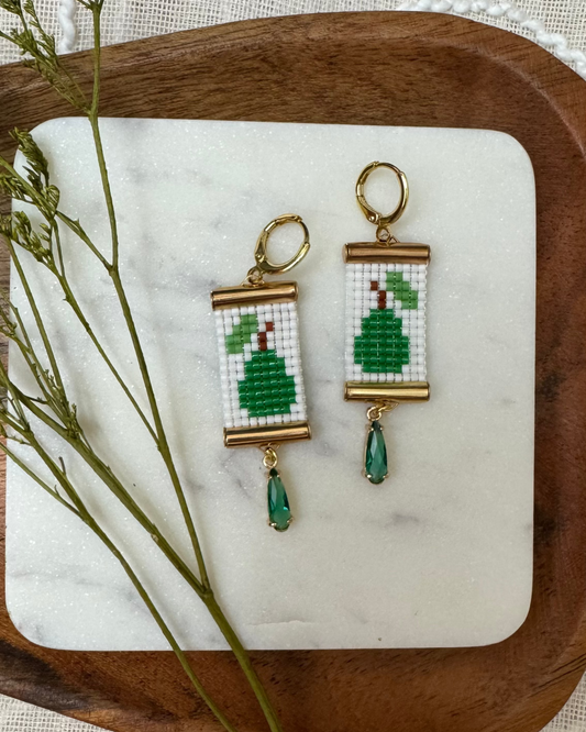 Pair of beaded earrings with green pear design on a marble tray with a wooden border.