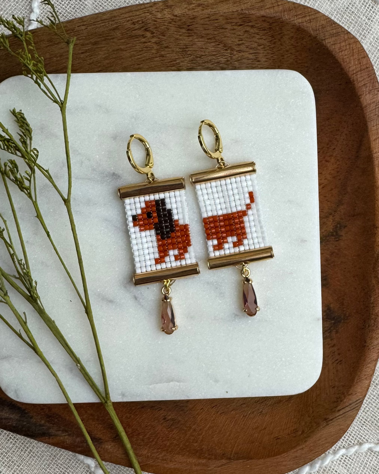 Pair of earrings with beaded daschund design on a wooden tray