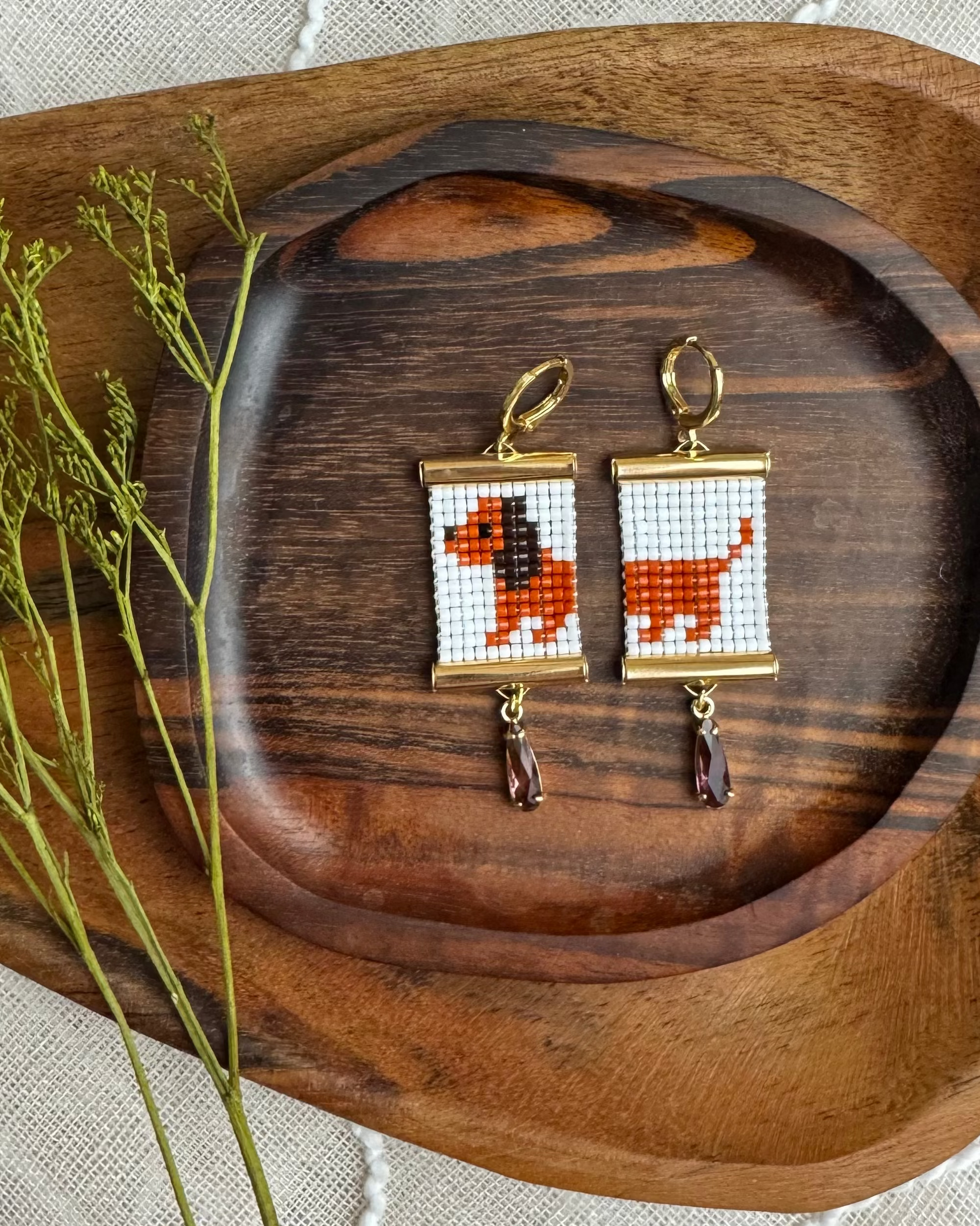 Pair of beaded earrings with dog design on a wooden tray