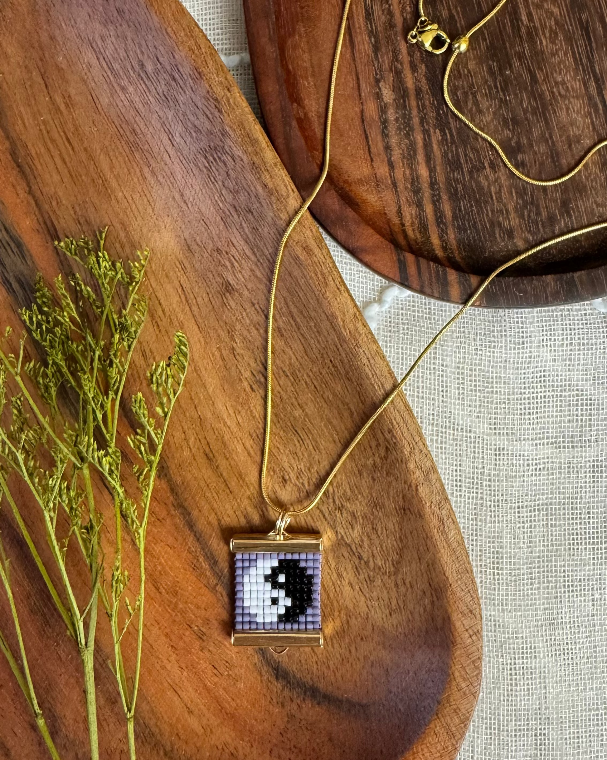 Necklace with a beaded yin yang pendant on a wooden surface