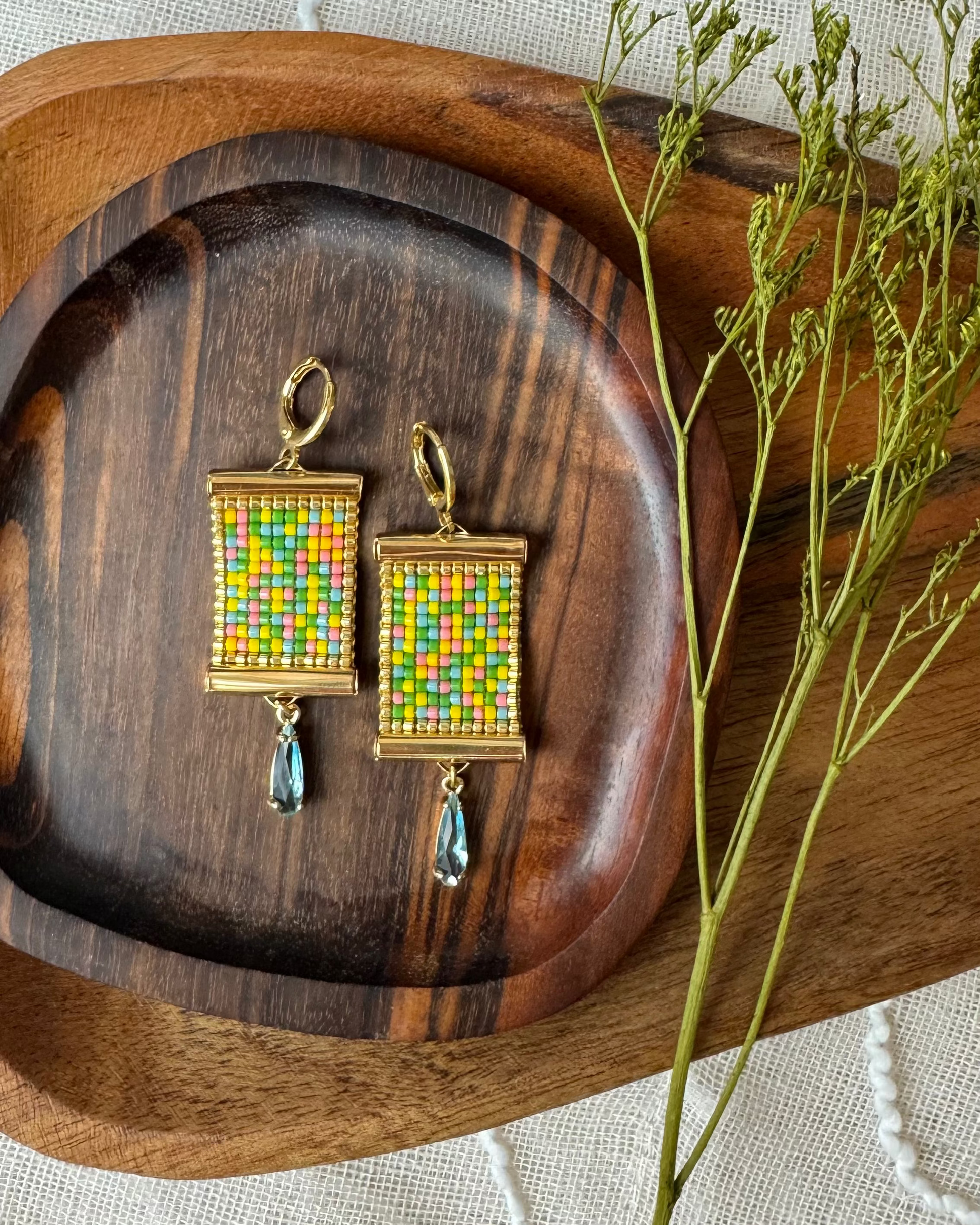 Colorful beaded earrings on a wooden tray with a natural background