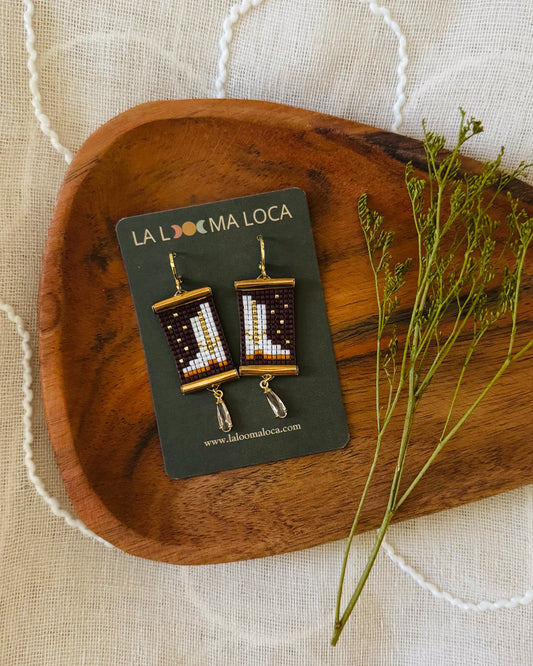 Beaded earrings depicting white cowgirl boots with a dark background.